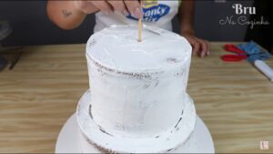 Depois que você cortar seu palito de churrasco na altura exata, centralize-o  no meio do seu bolo e o afunde.
